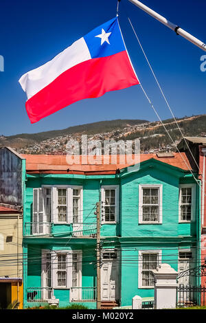 Rosso, bianco e blu bandiera cilena svolazzanti su un montante anteriore del tradizionale legno vecchio edificio sulla strada collinare a Valparaiso, Cile, Sud Foto Stock