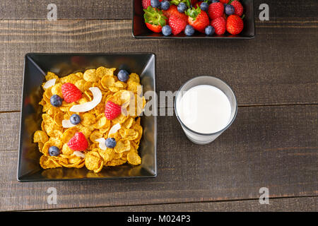 Cereali e frutti di bosco in un quadrato nero ciotola prima colazione al mattino con latte Foto Stock