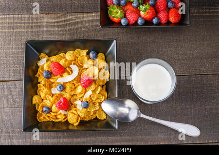 Cereali e frutti di bosco in un quadrato nero ciotola prima colazione al mattino con latte Foto Stock