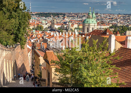 Turisti e visitatori che salgono i ripidi gradini che conducono verso il castello di Praga da Lesser Town, con la città vecchia di Praga in lontananza, Praga Foto Stock