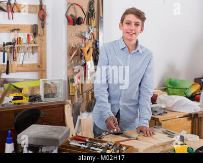 Allegro spagnolo adolescente sorridente e la lavorazione del legno in officina Foto Stock