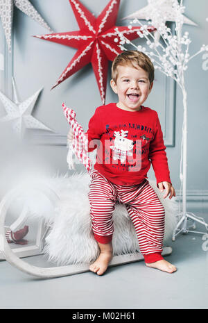 Allegro bambino seduto su una slitta di natale Foto Stock