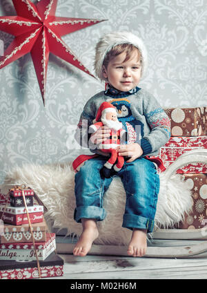 Allegro ragazzo seduto su una slitta di natale Foto Stock