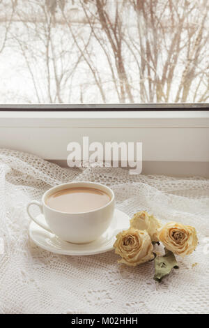 Tazza di caffè con il latte sul davanzale a secco con rose come decor sul Pizzo. Vintage. Foto Stock