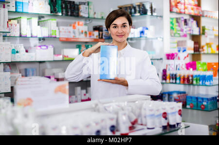 Felice allegro farmacista femmina suggerendo utili prodotti per la cura del corpo in farmacia Foto Stock