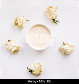 Ancora la vita di una tazza di caffè o cappuccino a secco con rose bianche intorno a. Square. Vista dall'alto. Foto Stock