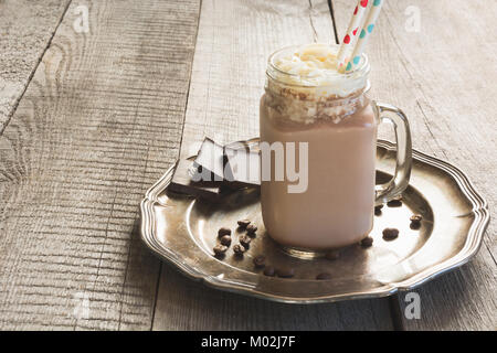 Cioccolato frullato di caffè con panna montata servita in vetro mason jar sul grigio Sfondo di legno. Bevanda dolce. Foto Stock