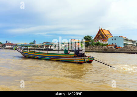 Asia,Thailandia, Bangkok,tipica barca sul fiume Chao Phraya,tempio buddista sullo sfondo Foto Stock