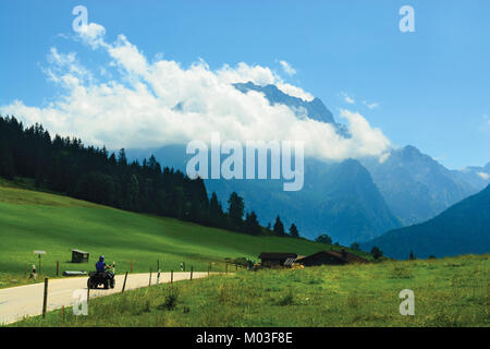 Strada che conduce attraverso i prati alpini a blue mountain top coperto con il cloud Foto Stock