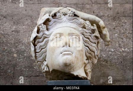 Testa - frammento di statua romana - Dio da antica Corinto Grecia con fiori o le uve in capelli ondulati e parte di una mano Foto Stock