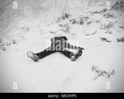 Ragazzo divertente in posa il cumulo di neve. Kid giochi fresco in polvere di neve su terreni sassosi hill. Tempesta di neve e nebbioso meteo. Foto Stock