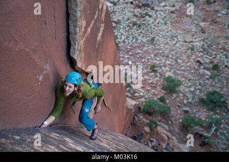 Un uomo si arrampica a crack in Indian Creek, Moab. Foto Stock