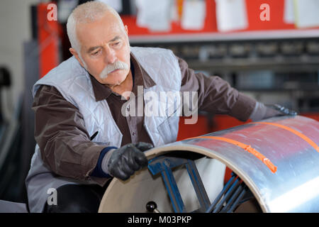 Senior lavoratore manuale movimentazione di bombole di gas in industria del metallo Foto Stock