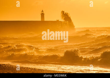 Newhaven, East Sussex. 18th gennaio 2018. UK Weather.INIZIO luminoso della giornata sulla costa meridionale. Le gales notturne si placano lasciando un vento a ovest che frusta il surf retroilluminato dal bagliore arancione del Sole nascente. Foto Stock