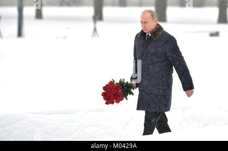 San Pietroburgo, Russia. 18 gennaio, 2018. Il presidente russo Vladimir Putin passeggiate con rose rosse durante una cerimonia che si terrà nel corso di una giornata nevosa presso il Cimitero di Piskarevskoye Gennaio 18, 2018 a San Pietroburgo, Russia. Putin ha partecipato gli eventi che segna il settantacinquesimo anniversario della fine della i nazisti assedio di Leningrado chiamato ora a San Pietroburgo. Credito: Planetpix/Alamy Live News Foto Stock