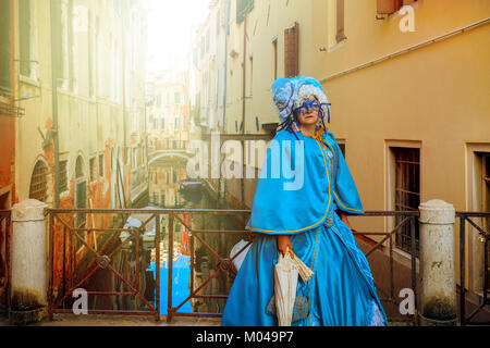 Venezia, Italia - 18 febbraio 2017: Unidentified donna vintage indossare il costume e la maschera in posa sul piccolo ponte sullo stretto canale. Foto Stock