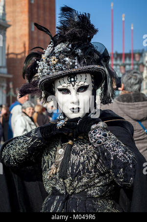 Venezia, Italia - 18 febbraio 2017: verticale orientato ritratto di una donna non identificato usura vintage costume nero, guanti, cappello e maschera bianca. Foto Stock