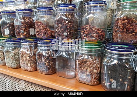 Un sacco di erbe essiccate e tisane in vasi su scaffali in un mercato di fattoria. Foto Stock