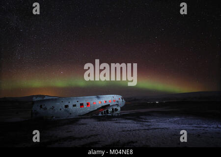 Aurora boreale, o luci del nord, brillano sopra il piano relitto di un US Navy aereo - un Super Douglas DC-3 - sulla spiaggia nera di Solheimasandur, sud dell'Islanda. Foto Stock