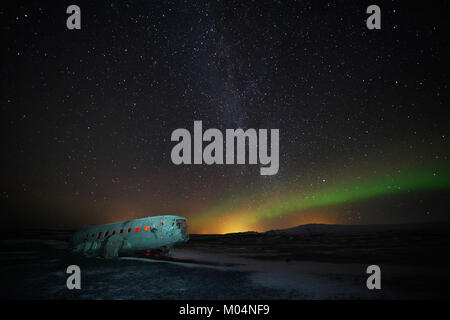 Aurora boreale, o luci del nord, brillano sopra il piano relitto di un US Navy aereo - un Super Douglas DC-3 - sulla spiaggia nera di Solheimasandur, sud dell'Islanda. Foto Stock