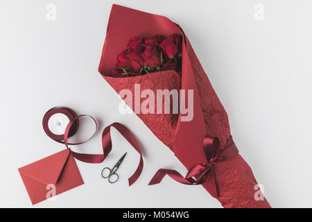 Lay piatto con bouquet di rose, nastro e involucro isolato su bianco, st Valentines Day holiday concept Foto Stock