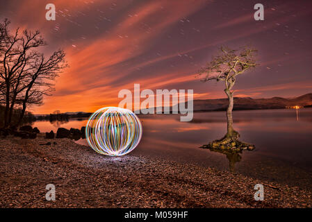 La pittura di luce sfera al tramonto sulla baia Millarochy, Loch Lomond, Scozia. Foto Stock