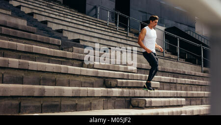 Runner correndo giù i passi dello stadio si erge come parte del suo addestramento fisico. giovane uomo in esecuzione al piano di sotto sul Stadium. Foto Stock