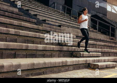 Runner correndo giù i passi dello stadio si erge come parte del suo allenamento fisico. Giovane uomo che corre al piano di sotto sul Stadium. Foto Stock