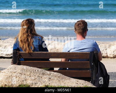 Due amici seduti su una panchina sul lungomare su un perfetto giorno chiaro guardando il mare Foto Stock