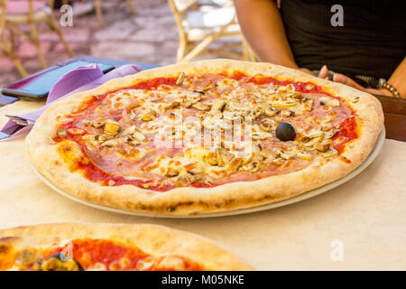 Pizza con funghi e prosciutto su un piatto in un ristorante Foto Stock