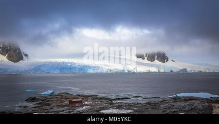 Costa rocciosa panorama di montagne e ghiacciai nascosti nelle nuvole, Peterman island, penisola Antartica Foto Stock