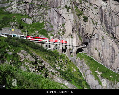 ANDERMATT, Svizzera Europa su luglio 2017: Express San Gottardo treno su Teufelsbruecke, Devil's ponte ferroviario e tunnel, Alpi svizzere. Foto Stock