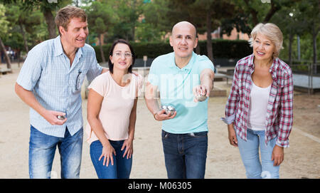 Allegro maschi e femmine giocando a bocce in th park nei giorni festivi Foto Stock