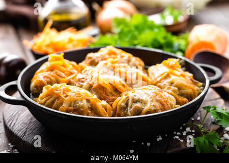 Involtini di cavolo stufato con la carne e le verdure in padella in scuro dello sfondo in legno Foto Stock