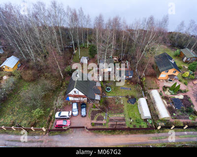 Casa in legno con cortile, fienili e piccolo giardino è su un lago. Vista aerea alla stagione primaverile. La Russia Foto Stock