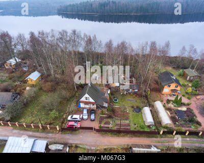 Cottage estivi con cortile, fienili e piccolo giardino è su un lago. Vista aerea alla stagione primaverile. La Russia Foto Stock