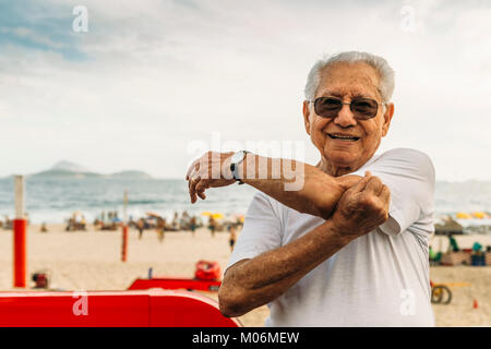 Modello rilasciato - Chiusura del vecchio (80-89) stretching tricipiti a lato della spiaggia di Rio de Janeiro, Brasile Foto Stock