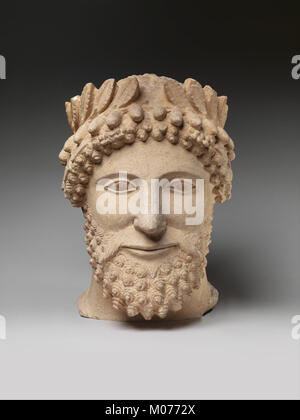 Una scultura in pietra calcarea raffigurante un uomo barbuto che indossa una corona, che riflette antichi stili artistici nella ritrattistica. Foto Stock