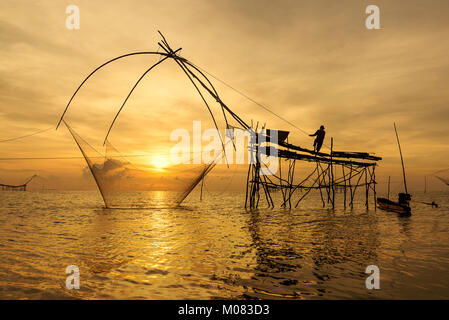 I pescatori intingere la sua rete di sollevamento in acqua per la cattura di gamberetti all'alba ,Phatthalung Thailandia Foto Stock