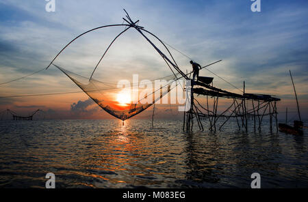 I pescatori intingere la sua rete di sollevamento in acqua per la cattura di gamberetti all'alba ,Phatthalung Thailandia Foto Stock