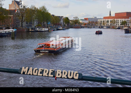 Gita in barca sul fiume Amstel da Magere Brug (skinny bridge) un pedone e bicicletta ponte a bilico, Amsterdam, Paesi Bassi Foto Stock