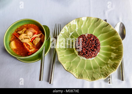 Riso marrone e bianco con riso tailandese zuppa popolare, chiamato Tom Yum Kung zuppa su tessuto bianco platemat Foto Stock