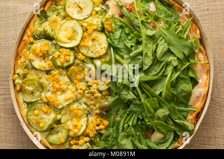 Due pizza sapore: metà la rucola e l altra metà zucchine con chicchi di mais. Vista dall'alto il dettaglio del pasto. Foto Stock