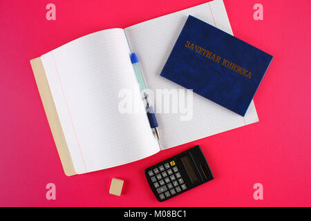 Un libro blu con una scritta in russo - uno studente il record di un libro. Penna, calcolatrice e i notebook in bianco su sfondo rosa. Gli studenti" Giorno Foto Stock