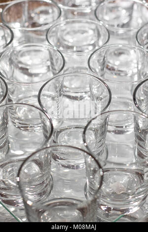 Array di bicchierini su tavolo bianco - colori metallici. Bicchieri fianco a fianco e riflettendo in ogni altro. Foto Stock