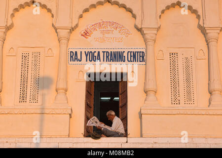 Istruttore Yoga lettura nel sole, Pushkar, Rajasthan, India Foto Stock