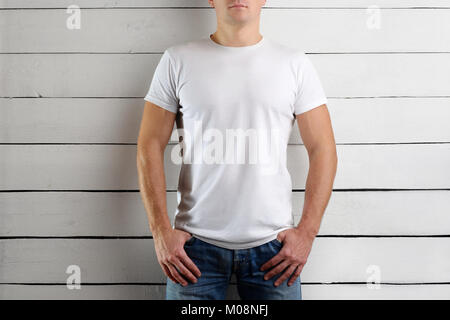 Giovane uomo in una T-shirt bianco su una luce sullo sfondo di legno. Mockup vestiti Foto Stock
