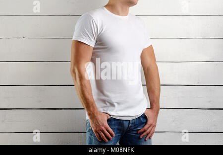 Uomo muscolare in una t-shirt bianco su uno sfondo di legno. Mockup vestiti Foto Stock