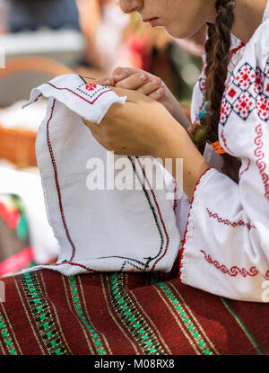 Giovane donna vestita di un folk rumena porta, lavorando manualmente in una spilla Foto Stock