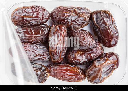 Medjool date in un contenitore in plastica su sfondo bianco Foto Stock